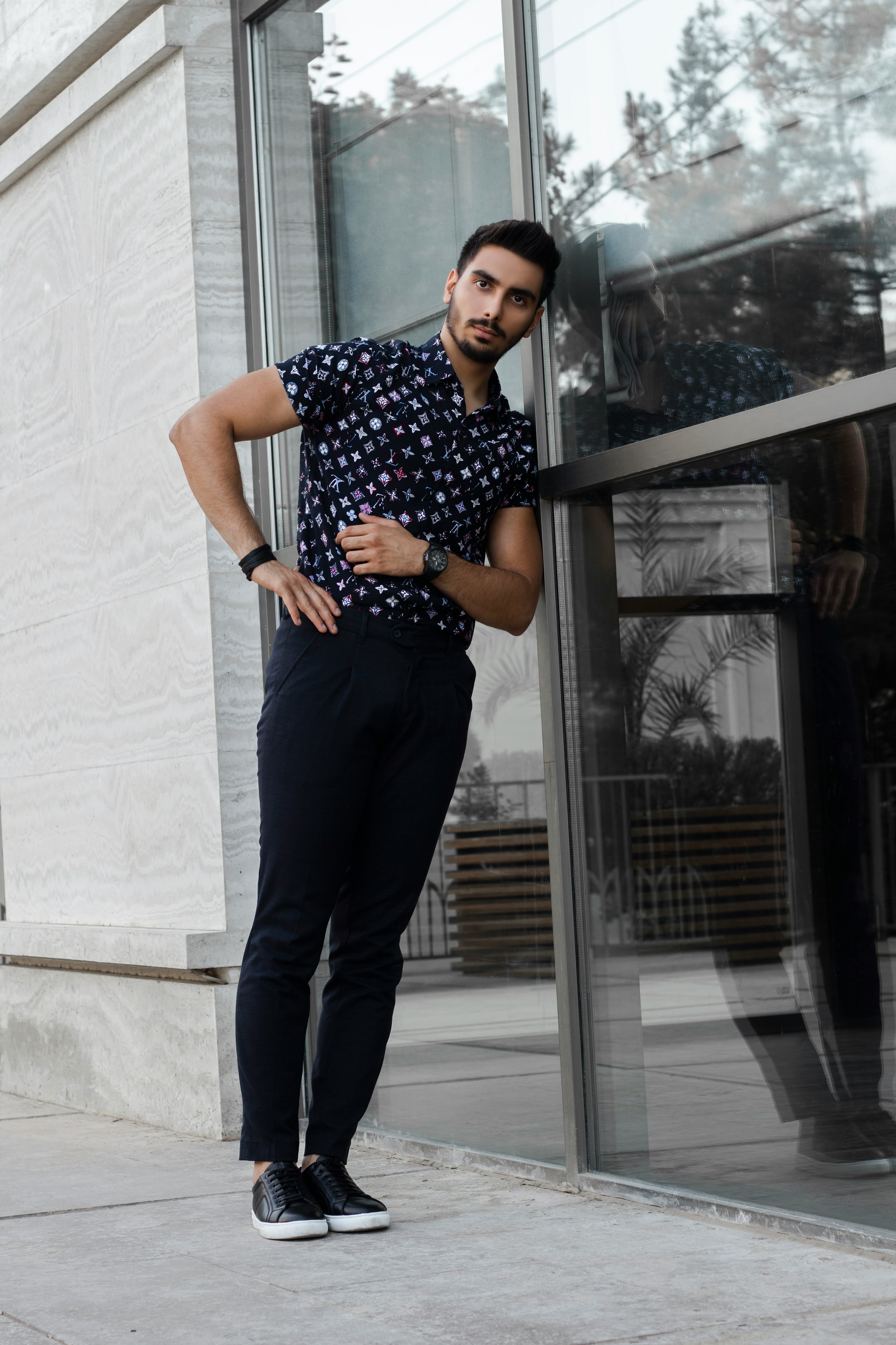 woman in black and white polka dot shirt and blue denim jeans standing beside glass window